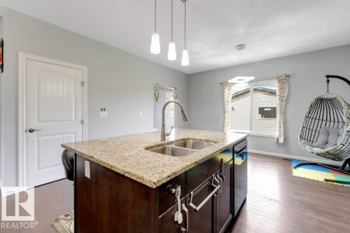 Kitchen island featuring a granite countertop, double stainless steel sink, and a gooseneck faucet - 2436 18 Avenue Nw, Edmonton, AB 