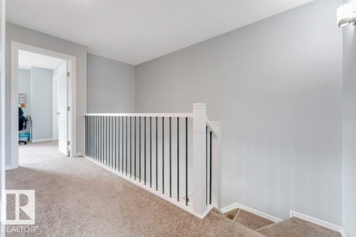 Carpeted landing with white railing and dark balusters - 2436 18 Avenue Nw, Edmonton, AB 