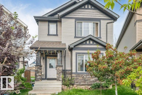 Two-story residence featuring light gray siding, dark trim, and a stone facade - 2436 18 Avenue Nw, Edmonton, AB 