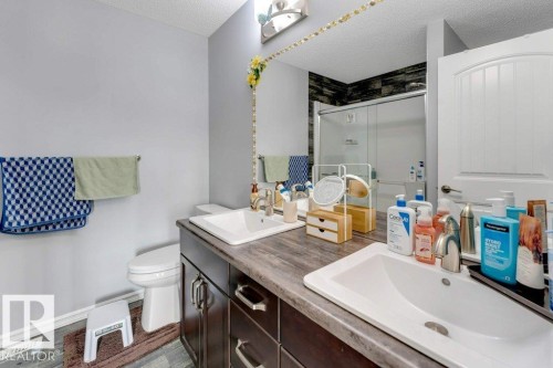 Dual vanity with integrated sinks, dark wood-finish cabinetry, and a full-width mirror - 2436 18 Avenue Nw, Edmonton, AB 
