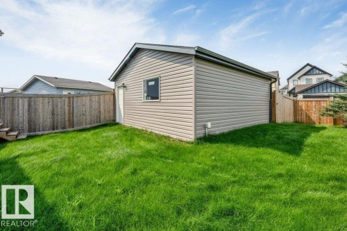Detached accessory building with horizontal siding and a single window, surrounded by a wood fence and a green lawn - 2436 18 Avenue Nw, Edmonton, AB 