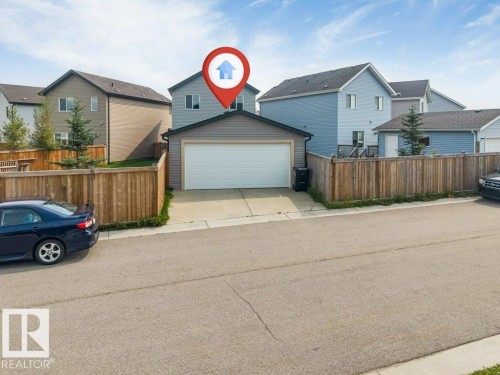 Exterior featuring a two-story design, attached garage, concrete driveway, and wood privacy fencing - 2436 18 Avenue Nw, Edmonton, AB 