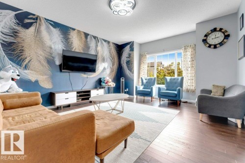 Bright living area featuring a large window, dark wood-finish flooring, and a contemporary ceiling fixture - 2436 18 Avenue Nw, Edmonton, AB 