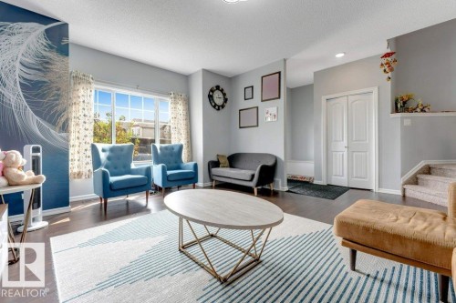 Expansive window with grid panes, dark wood-finish flooring, two-panel bifold doors, and a staircase with carpeted treads - 2436 18 Avenue Nw, Edmonton, AB 