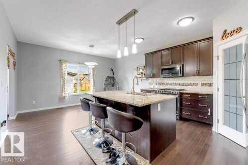 Kitchen island with a light-toned countertop, pendant lighting, and stainless steel appliances - 2436 18 Avenue Nw, Edmonton, AB 