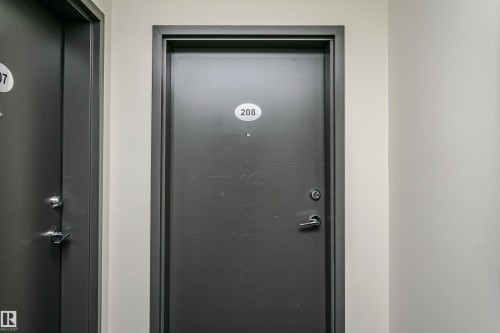 Gray entry door with a door number plaque, complemented by a contemporary handle and deadbolt hardware - #208 9907 91 Av Nw, Edmonton, AB - Indoor