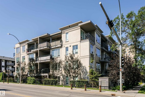 Multi-story building featuring a light-toned facade, multiple balconies with metal railings, and large windows - #208 9907 91 Av Nw, Edmonton, AB - Outdoor With Balcony With Facade