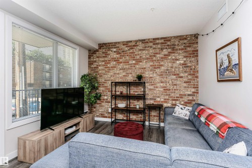 Exposed brick accent wall with a large window featuring horizontal blinds - #208 9907 91 Av Nw, Edmonton, AB - Indoor Photo Showing Other Room