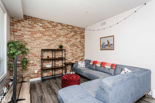 Exposed brick accent wall complementing the wood-finish flooring - #208 9907 91 Av Nw, Edmonton, AB - Indoor Photo Showing Living Room