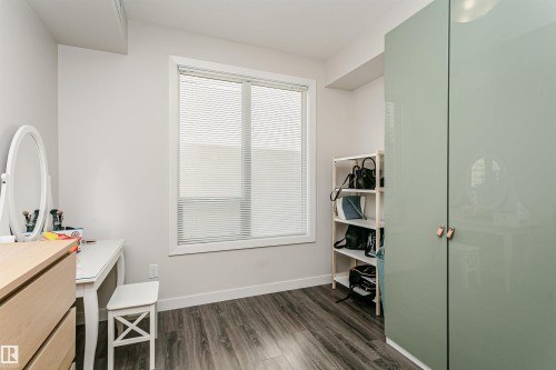 Room featuring wood-finish flooring and a large window with blinds - #208 9907 91 Av Nw, Edmonton, AB - Indoor Photo Showing Other Room
