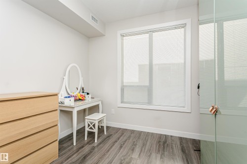 Interior space featuring wood-finish flooring, a broad window with horizontal blinds, and a built-in glass panel - #208 9907 91 Av Nw, Edmonton, AB - Indoor