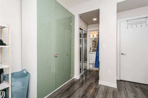 Entryway featuring wood-finish flooring, built-in cabinetry with light green doors and contrasting pulls, and a recessed lighting fixture - #208 9907 91 Av Nw, Edmonton, AB - Indoor Photo Showing Other Room