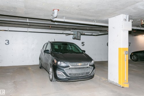 Underground parking garage featuring concrete walls, concrete ceiling, and exposed utility piping - #208 9907 91 Av Nw, Edmonton, AB - Indoor Photo Showing Garage