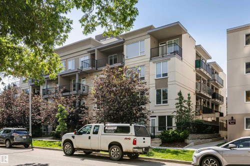 Modern multi-story building featuring light-colored stucco and stone accents - #208 9907 91 Av Nw, Edmonton, AB - Outdoor With Balcony
