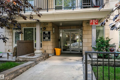 Building exterior featuring stone-look block siding and a ground-floor entrance with glass doors - #208 9907 91 Av Nw, Edmonton, AB - Outdoor With Balcony