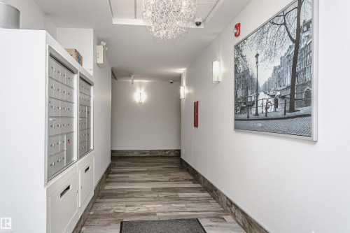 Entryway featuring wood-finish flooring, a contemporary chandelier, and wall-mounted sconces - #208 9907 91 Av Nw, Edmonton, AB - Indoor Photo Showing Other Room