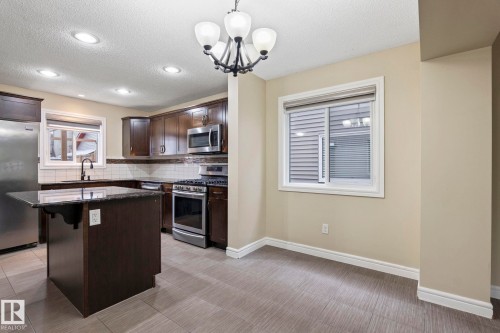 Kitchen featuring dark wood-finish cabinetry, stainless steel appliances, a center island with a dark countertop, white subway tile backsplash, and recessed lighting - 1209 30 Avenue Nw, Edmonton, AB - Indoor Photo Showing Kitchen With Upgraded Kitchen