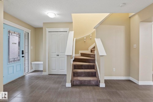 Entryway featuring large format tile flooring, a light blue front door with decorative glass, and a curved staircase with carpeted treads - 1209 30 Avenue Nw, Edmonton, AB - Indoor Photo Showing Other Room