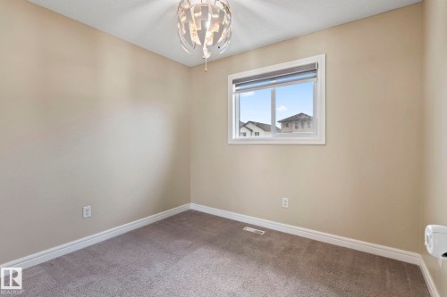 Neutral wall paint, plush carpet flooring, a contemporary ceiling light fixture, and a window with roller shade - 1209 30 Avenue Nw, Edmonton, AB - Indoor Photo Showing Other Room