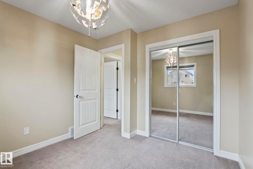 Neutral-toned carpeting, mirrored sliding closet doors, and a decorative ceiling light fixture - 1209 30 Avenue Nw, Edmonton, AB - Indoor Photo Showing Other Room
