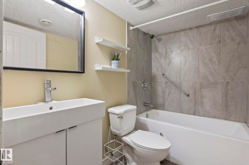 White vanity with a rectangular basin, chrome faucet, and framed mirror - 1209 30 Avenue Nw, Edmonton, AB - Indoor Photo Showing Bathroom
