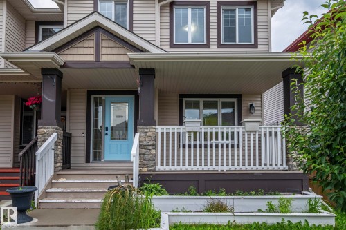 Welcoming covered porch with a light blue front door, stone accent columns, and white railing - 1209 30 Avenue Nw, Edmonton, AB - Outdoor With Deck Patio Veranda With Facade