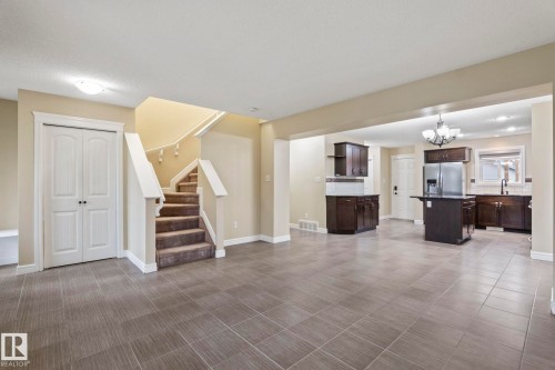 Open-concept layout with tile flooring, dark wood cabinetry, a central island, and stainless steel appliances - 1209 30 Avenue Nw, Edmonton, AB - Indoor