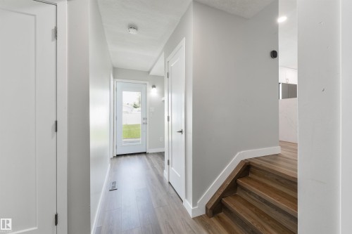Wood-finish flooring throughout, white interior doors, and a full-light rear door - 4614 53 Ave, Calmar, AB - Indoor Photo Showing Other Room
