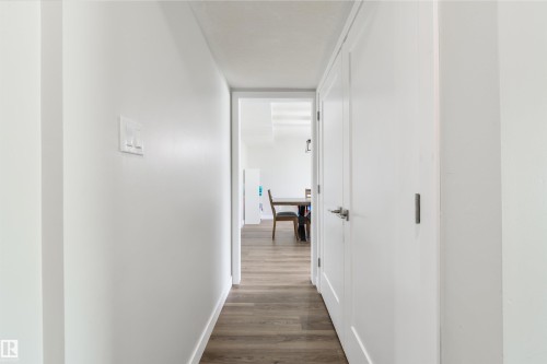 Hallway featuring wood-finish flooring, white walls, and white doors with contemporary hardware - 4614 53 Ave, Calmar, AB - Indoor Photo Showing Other Room