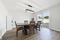 Wood-finish flooring, white walls, and a contemporary linear chandelier with a metal frame - 