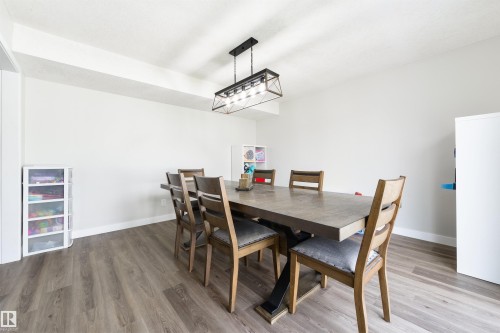 Wood-finish flooring with white baseboards, light-toned walls, and a contemporary ceiling light fixture - 4614 53 Ave, Calmar, AB - Indoor Photo Showing Dining Room