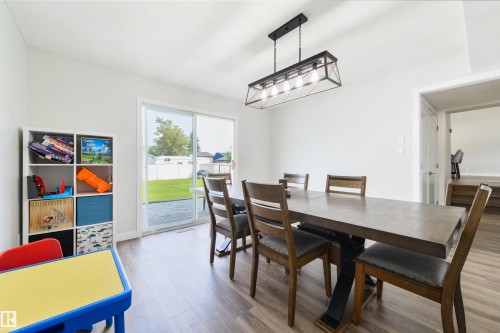 Spacious interior with wood-finish flooring, a contemporary linear chandelier, and sliding glass doors opening to the backyard - 4614 53 Ave, Calmar, AB - Indoor Photo Showing Dining Room