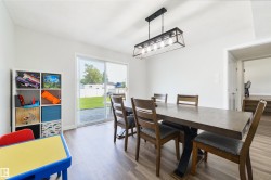 Spacious interior with wood-finish flooring, a contemporary linear chandelier, and sliding glass doors opening to the backyard - 