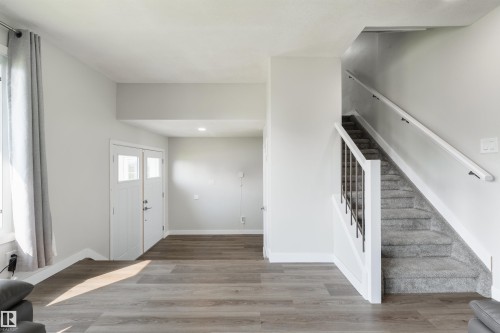 Wood-finish flooring, white trim, and a carpeted staircase with white railings - 4614 53 Ave, Calmar, AB - Indoor Photo Showing Other Room