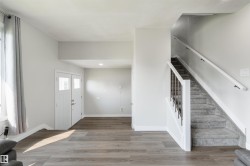 Wood-finish flooring, white trim, and a carpeted staircase with white railings - 