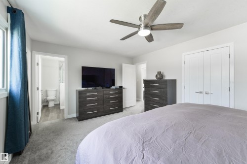 Neutral wall paint, ceiling fan with integrated lighting, window with white trim, gray carpet flooring, and white interior doors - 4614 53 Ave, Calmar, AB - Indoor Photo Showing Bedroom