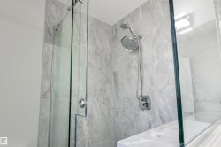 Frameless glass shower enclosure with a built-in bench, tiled walls, and a multi-function showerhead - 