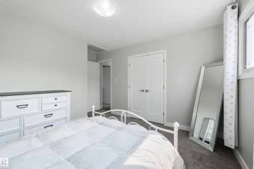 Light gray wall paint, textured gray carpeting, white double French doors, and a ceiling-mounted light fixture - 4614 53 Ave, Calmar, AB - Indoor Photo Showing Bedroom