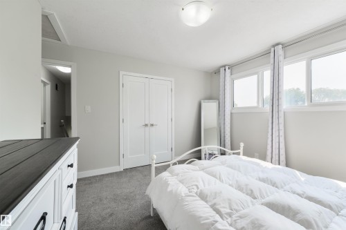 Recessed ceiling light, carpeted flooring, double bi-fold doors, multiple windows, and a flush mount light fixture - 4614 53 Ave, Calmar, AB - Indoor Photo Showing Bedroom