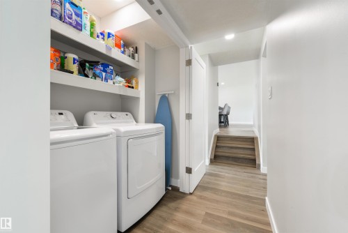 Laundry area featuring a side-by-side washer and dryer, built-in shelving, and wood-finish flooring - 4614 53 Ave, Calmar, AB - Indoor Photo Showing Laundry Room