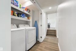 Laundry area featuring a side-by-side washer and dryer, built-in shelving, and wood-finish flooring - 