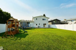 Expansive grassy yard with white privacy fencing and a rear deck - 