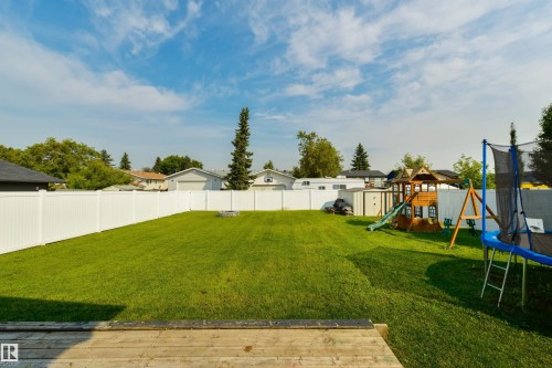 Expansive backyard featuring a manicured lawn, white privacy fencing, and a built-in fire pit - 4614 53 Ave, Calmar, AB - Outdoor With Backyard