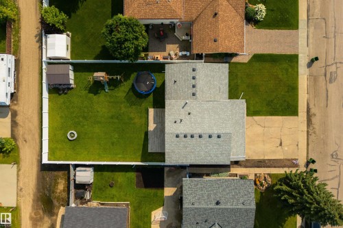 Expansive backyard featuring a green lawn, white privacy fencing, and a built-in fire pit - 4614 53 Ave, Calmar, AB - Outdoor