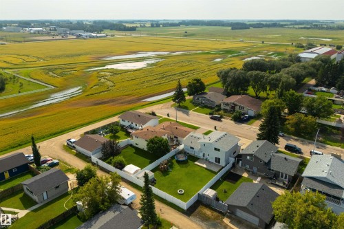 Aerial perspective showcasing residential properties with expansive green spaces and distant agricultural fields - 4614 53 Ave, Calmar, AB - Outdoor With View