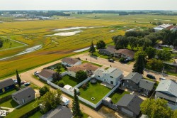 Aerial perspective showcasing residential properties with expansive green spaces and distant agricultural fields - 