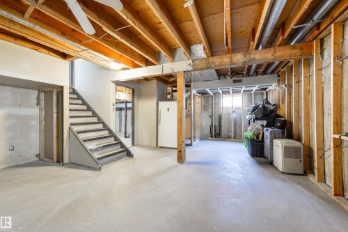 Unfinished basement with exposed wood joists and framing, a staircase with painted risers, and concrete flooring - 4614 53 Ave, Calmar, AB - Indoor Photo Showing Basement