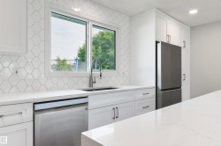 White shaker-style cabinetry, quartz countertops, hexagonal tile backsplash, stainless steel appliances, and an undermount sink with a gooseneck faucet - 