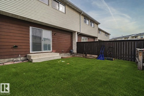 Manicured lawn with a privacy fence, concrete patio steps, and sliding glass door access - 221 Harrison Dr Nw, Edmonton, AB - Outdoor With Exterior