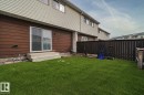 Manicured lawn with a privacy fence, concrete patio steps, and sliding glass door access - 221 Harrison Dr Nw, Edmonton, AB  - Outdoor With Exterior 